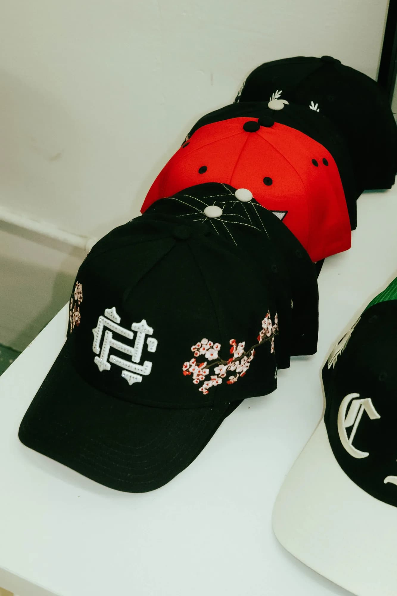 Assorted Common Hype caps with embroidered lettering and floral artwork