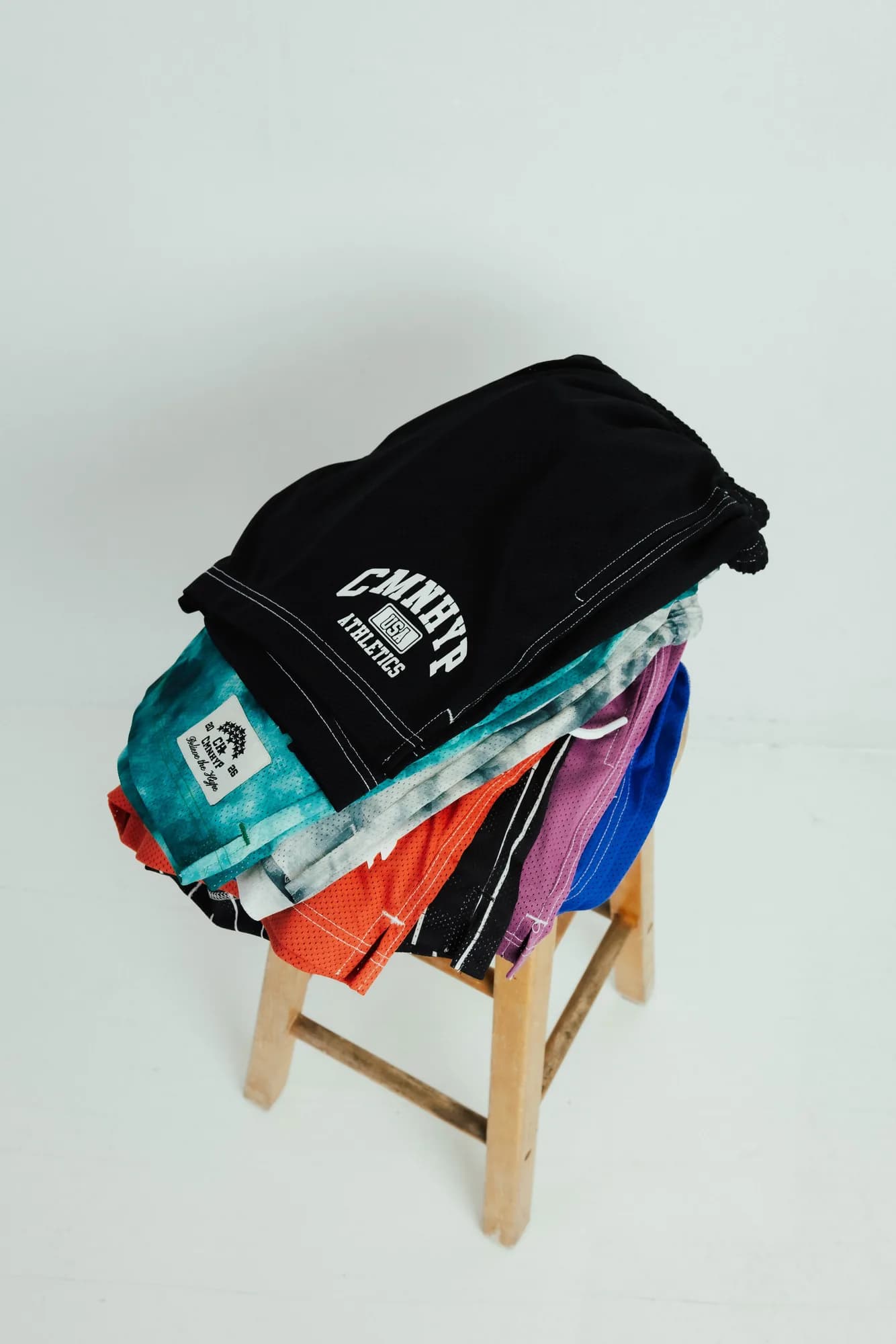 Folded Common Hype shorts in assorted colors stacked on a wooden stool