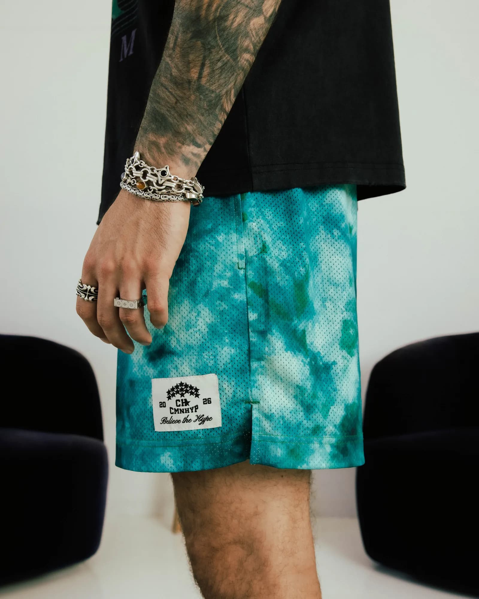 Model wearing turquoise patterned Common Hype shorts with a woven logo patch