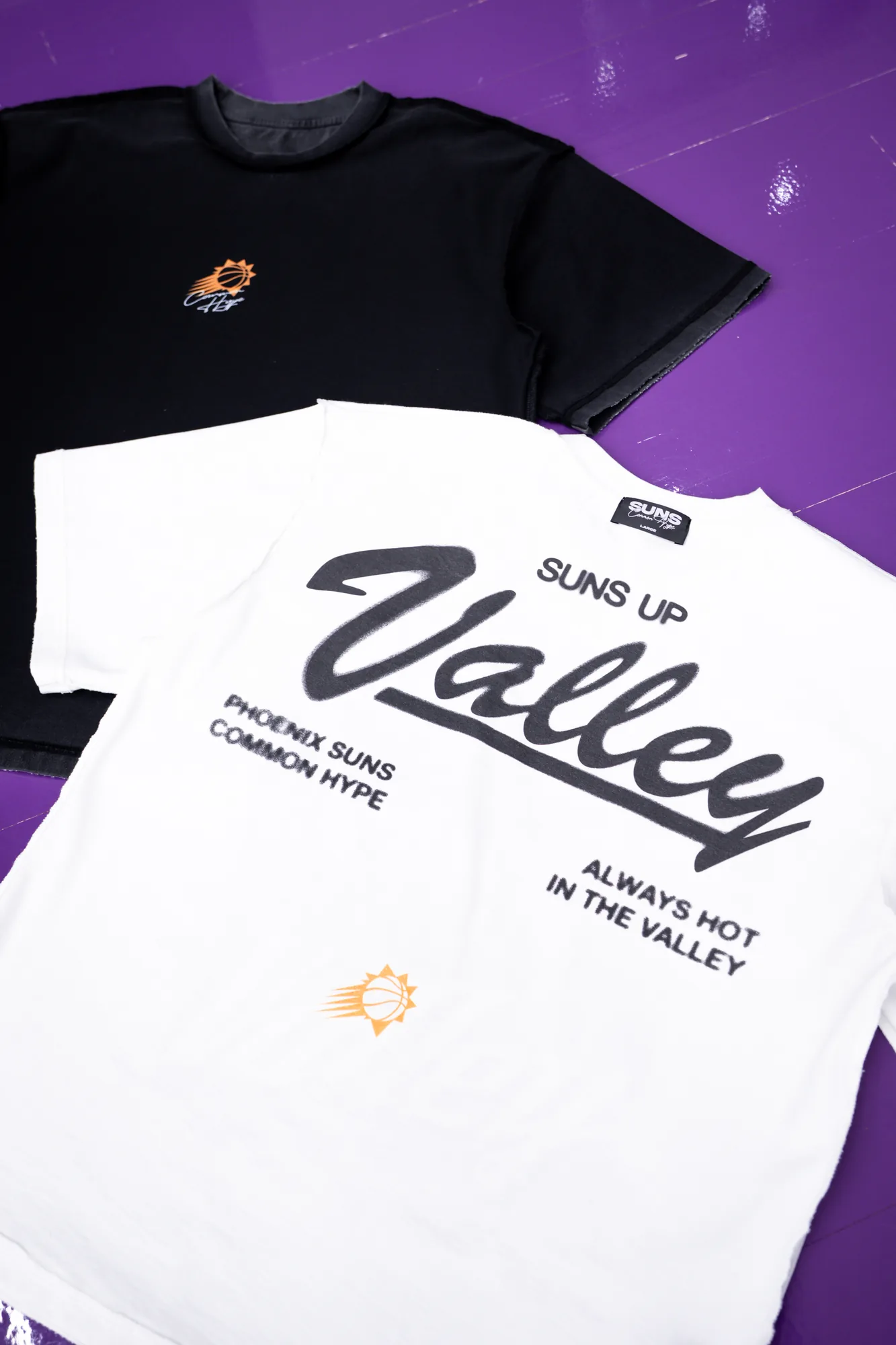 Black and white Common Hype Phoenix Suns tees displayed on a purple basketball court