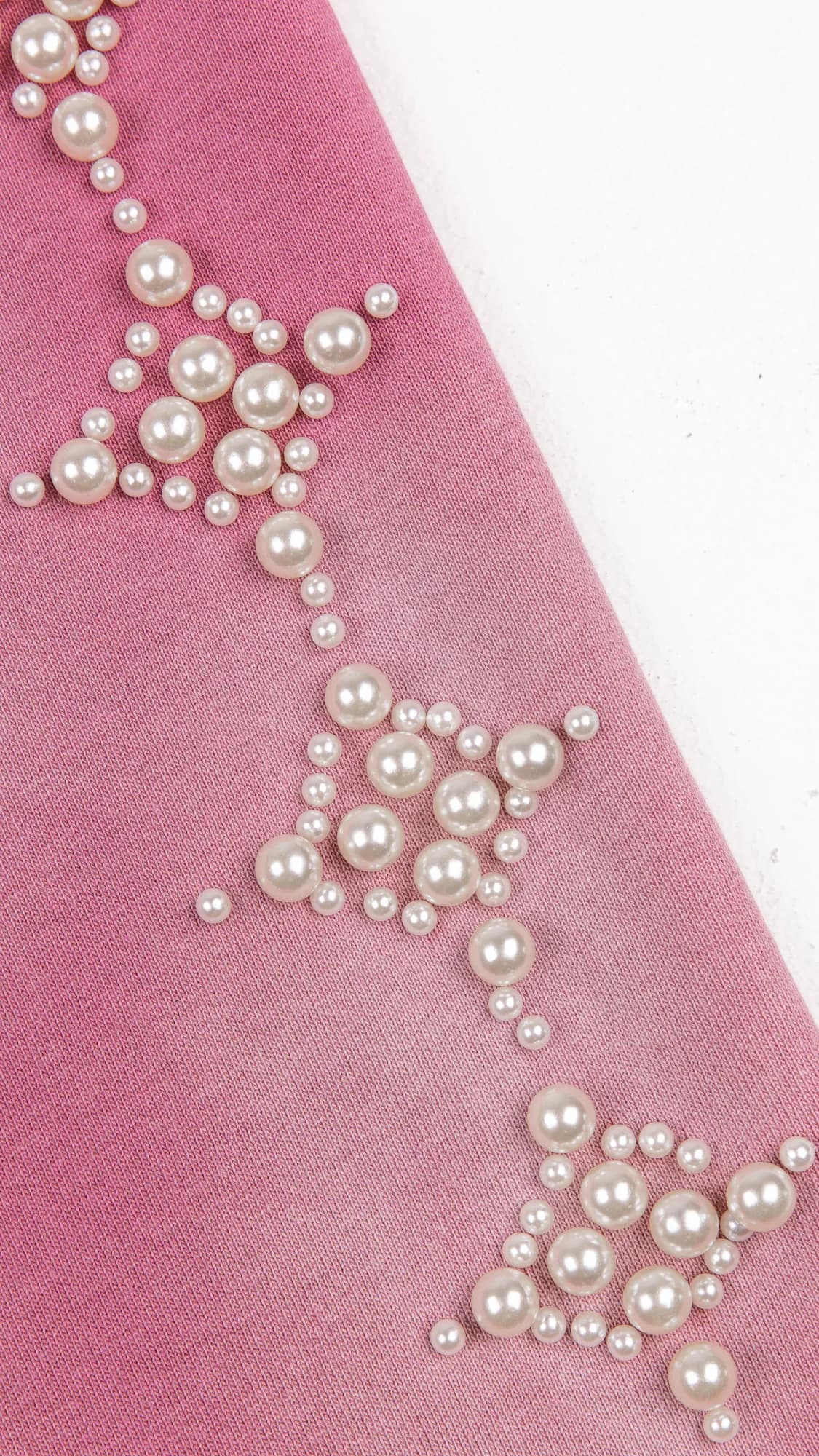 Pearl and silver star-shaped embellishments on pink Commons Studios fabric