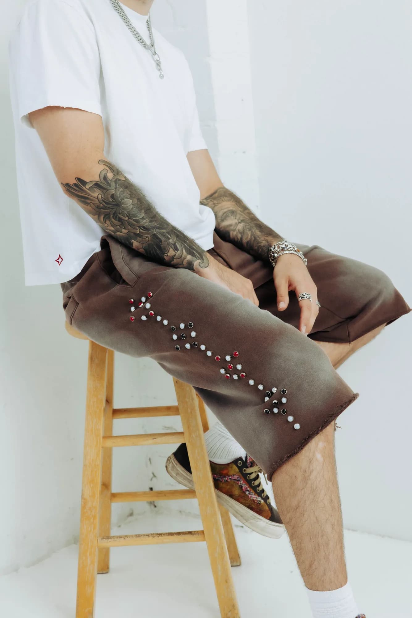 Model wearing brown Commons Studios shorts with silver embellishments