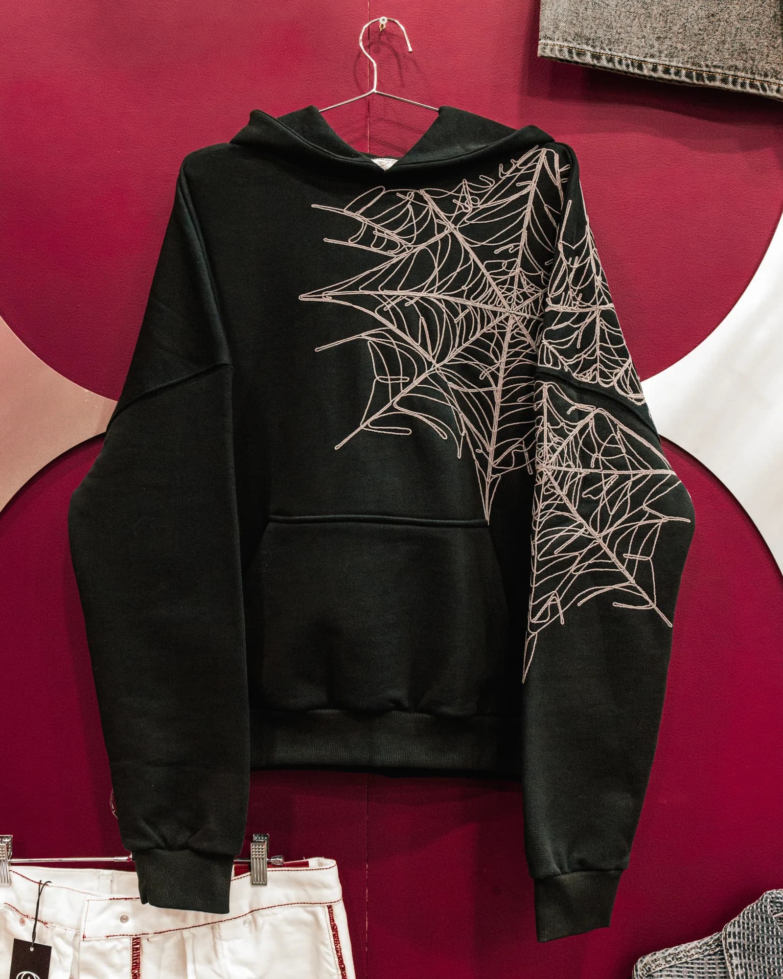 Black Commons Studios hoodie with a white web graphic displayed on a hanger