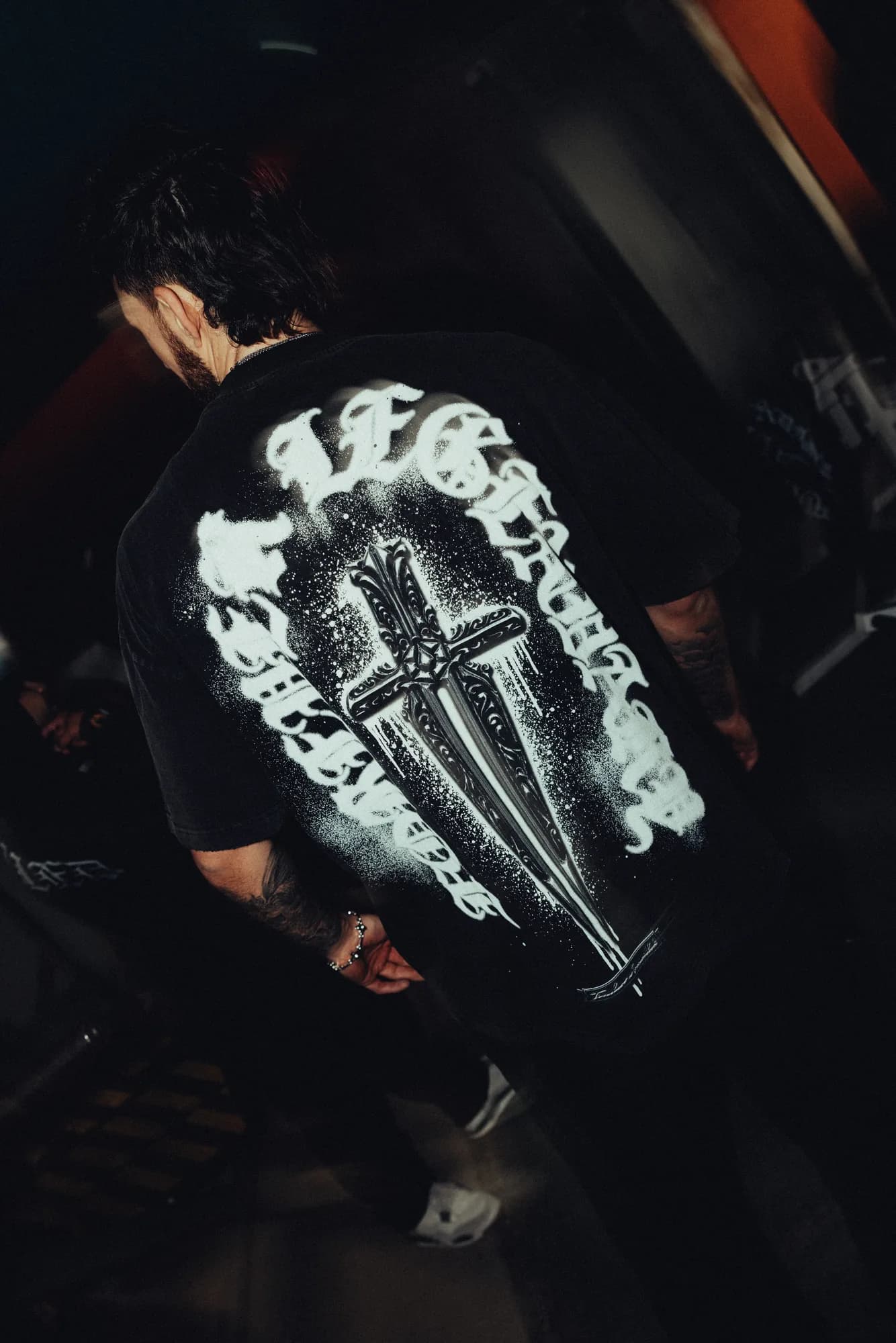 Model wearing a black Ironwilled tee with a large white sword graphic on the back