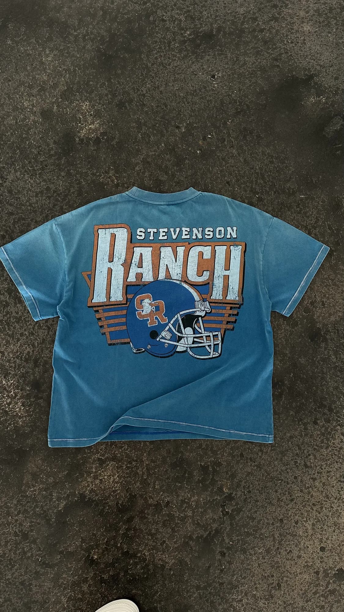 Blue Stevenson Ranch tee with a large football helmet graphic on the back