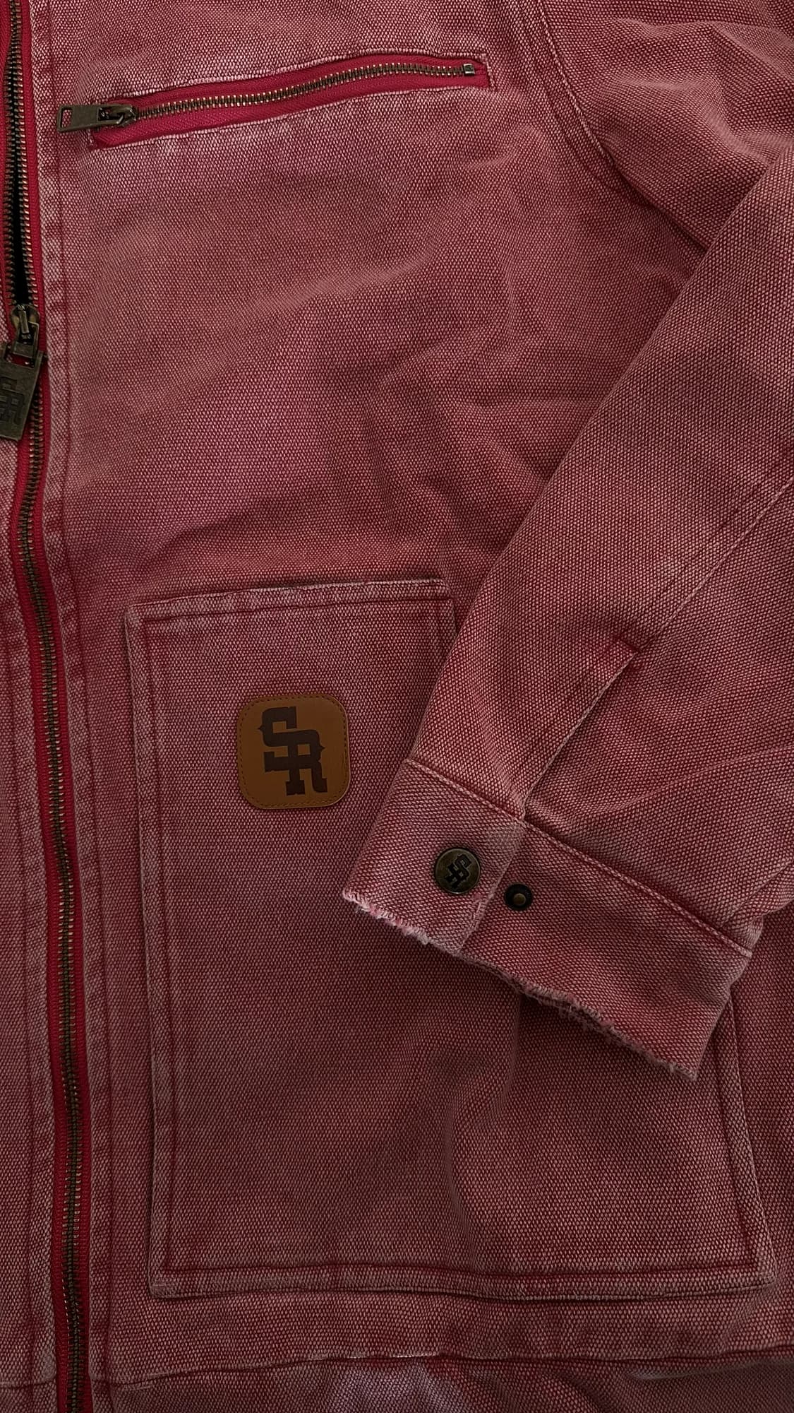 Close-up of washed red Stevenson Ranch workwear with a zip pocket and logo patch