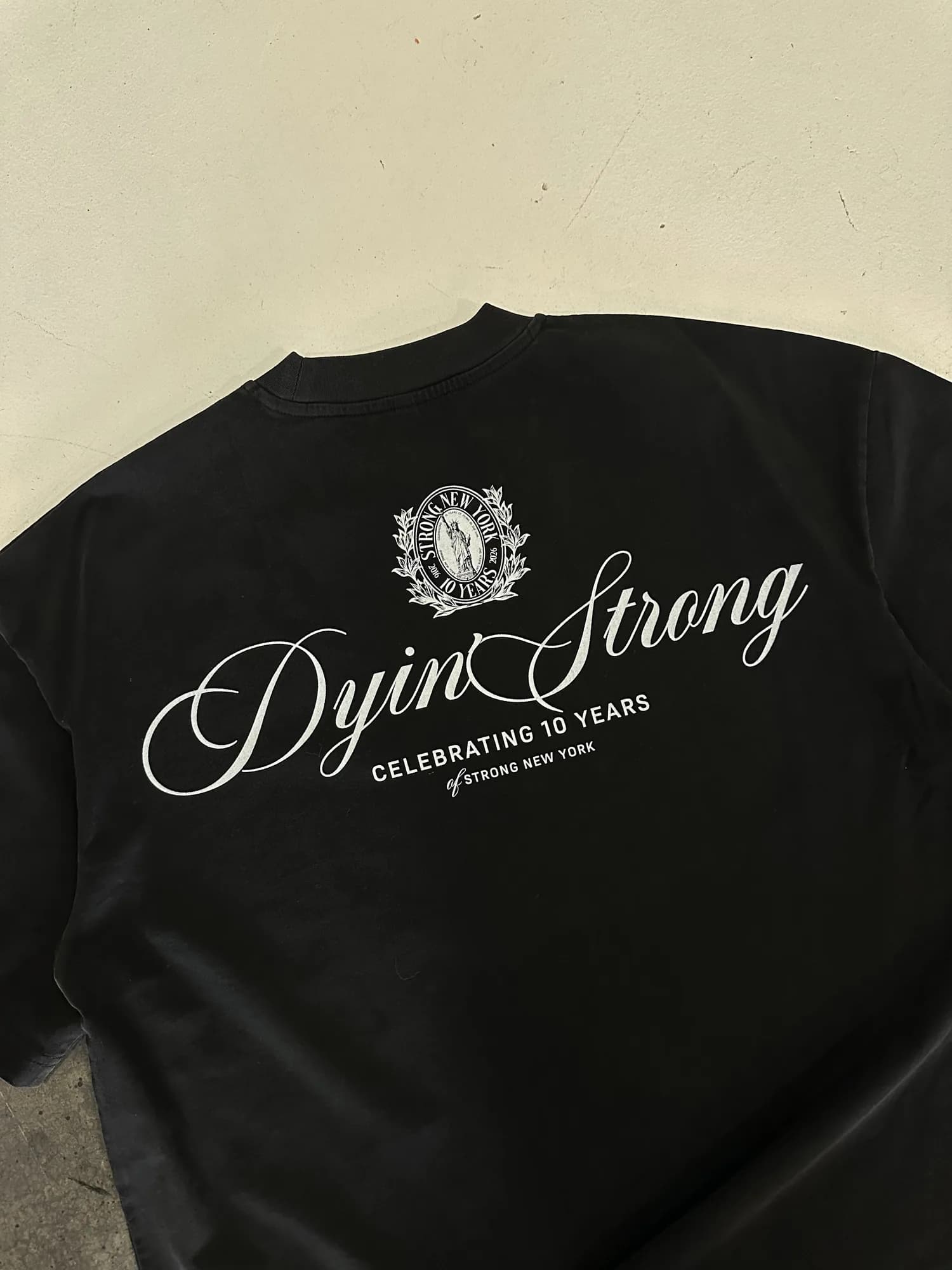 Black Strong New York tee with white script celebrating ten years