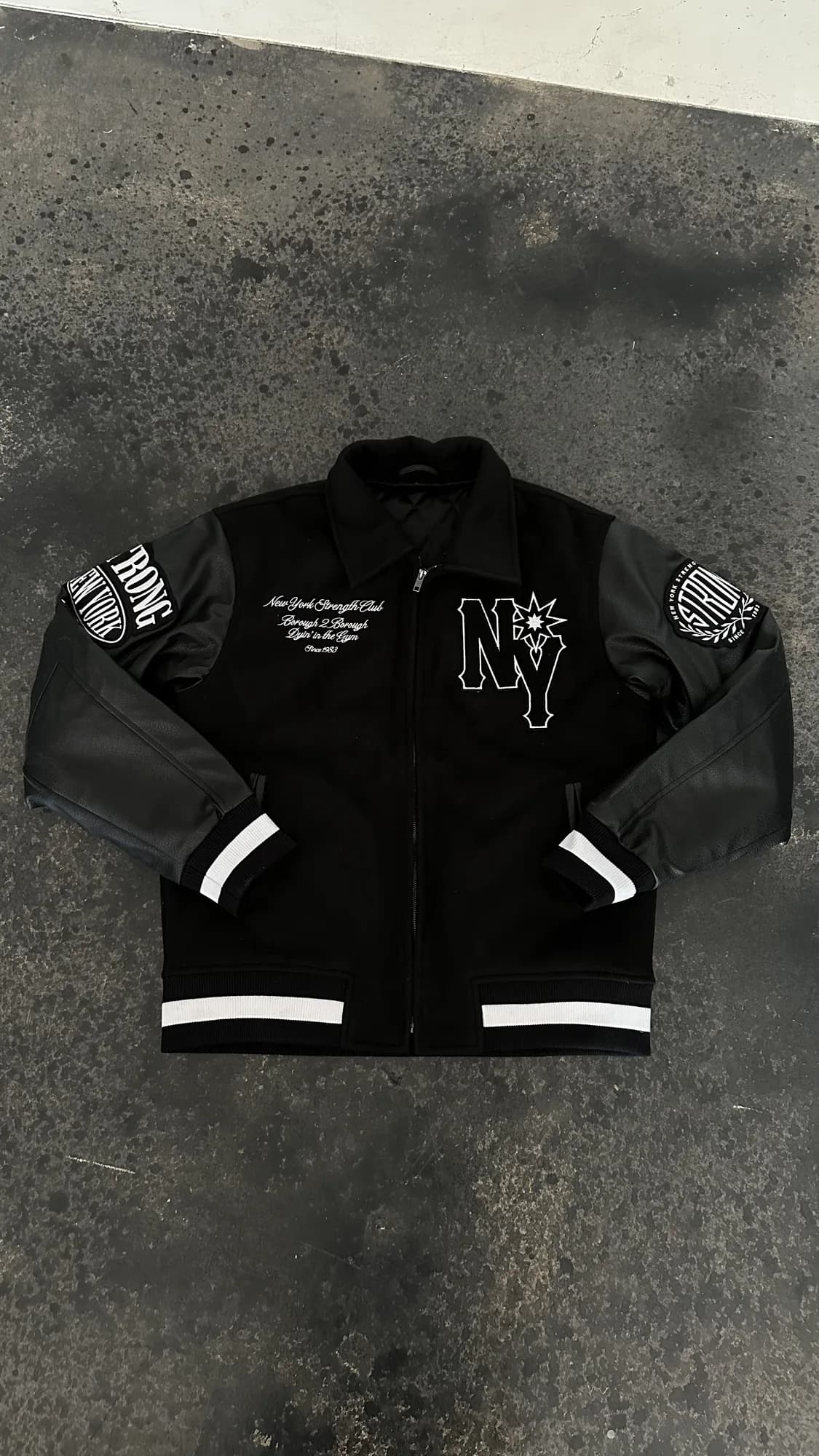 Black Strong New York varsity jacket with embroidered chest and sleeve patches
